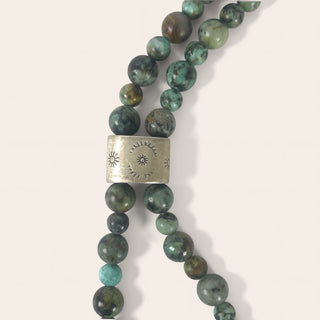 Necklace with green beads and a silver clasp on a light background