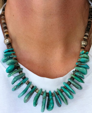 Turquoise beaded necklace worn by a person on a white background