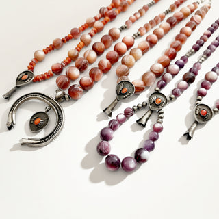Red and purple beaded jewelry on a beige background