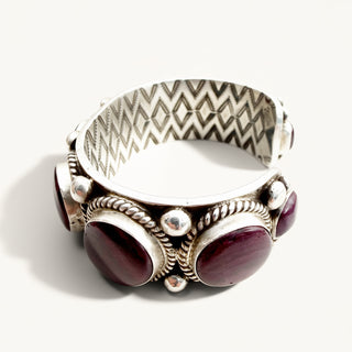 silver cuff with purple stones on a beige background