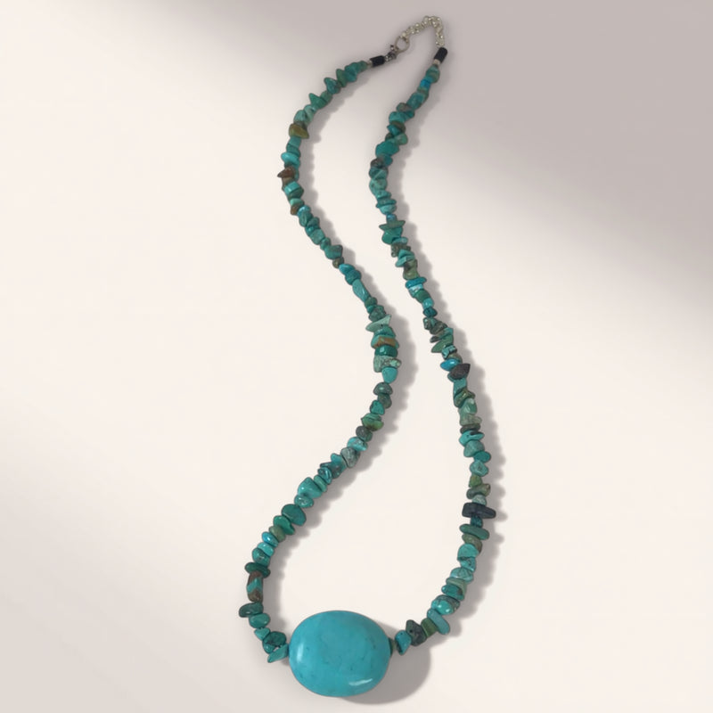 Turquoise beaded necklace with a large turquoise stone on a white background