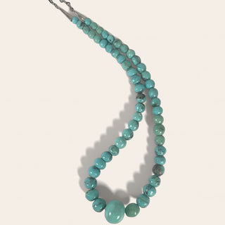 Turquoise beaded necklace on a light beige background