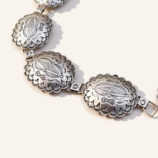 Silver jewelry with concho design on a beige background