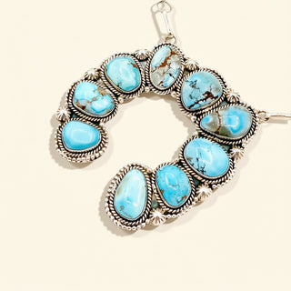 Silver necklace with turquoise stones on a beige background