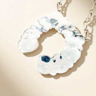 Silver pendant on a beige background