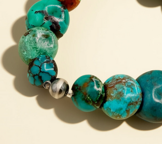 Turquoise beaded bracelet with a silver accent on a beige background