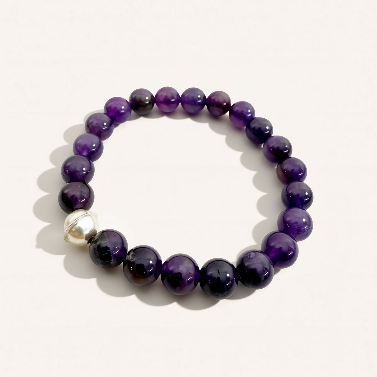Purple beaded bracelet with a silver clasp on a white background