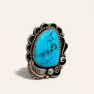 Turquoise stone ring with silver decorative band on beige background
