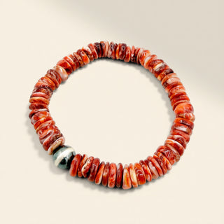 Beaded bracelet with red and white stones on a beige background