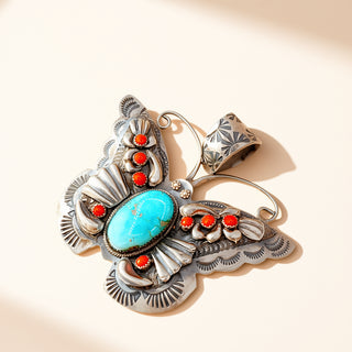 Butterfly pendant with red and turquoise stones on a beige background