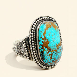 Turquoise stone cuff with silver band on a beige background