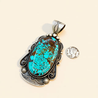 Turquoise pendant with silver frame on a beige background