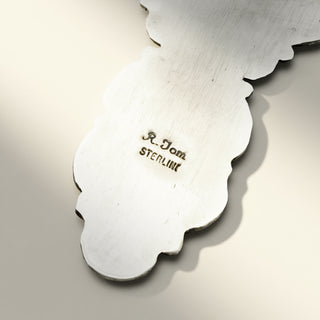 Close-up of a silver object with 'R. Tom' branding on a light background