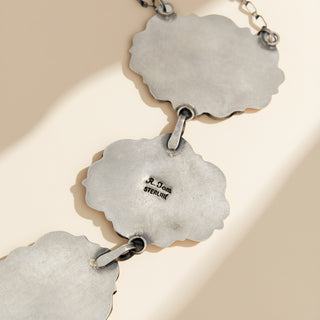 Close-up of silver jewelry with 'Sterling' marking on a beige background
