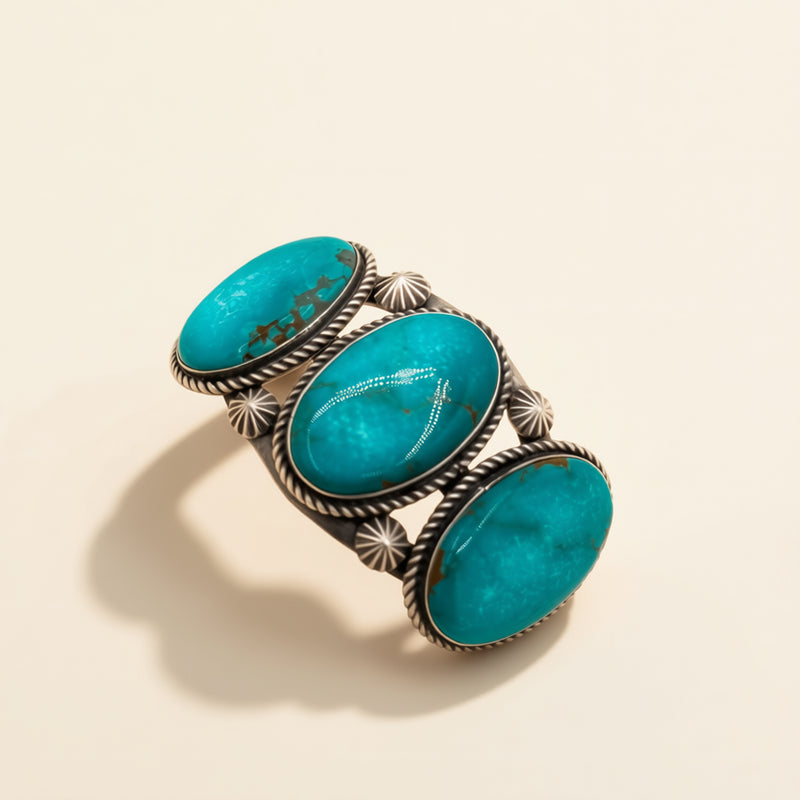 Turquoise stone cuff with silver band on a beige background