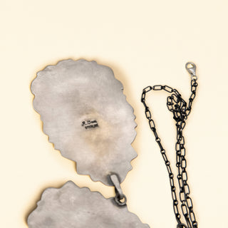 Metallic pendant with chain on a beige background