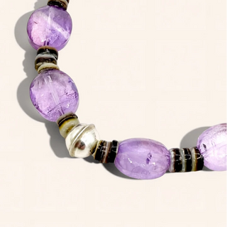 Purple beaded bracelet with black and gold accents on a white background