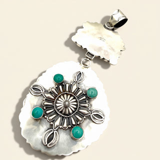 Silver pendant with turquoise stones on a beige background