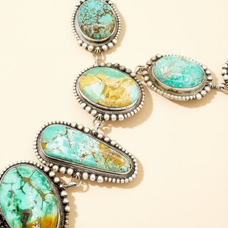 Jewelry set with turquoise stones and silver accents on a beige background