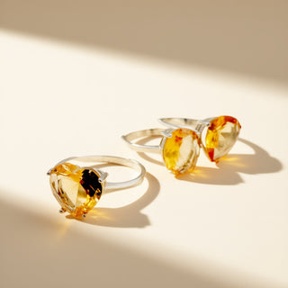 Three silver rings with yellow gemstones on a beige background