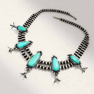 silver necklace with turquoise stones on a beige background