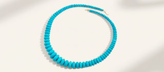 blue beaded necklace on a beige background