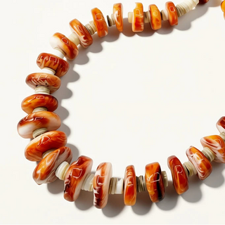 Necklace with orange and white beads on a light background