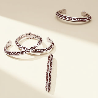 Silver cuffs with designs on a beige background