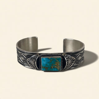 Silver bracelet with turquoise stone on a beige background