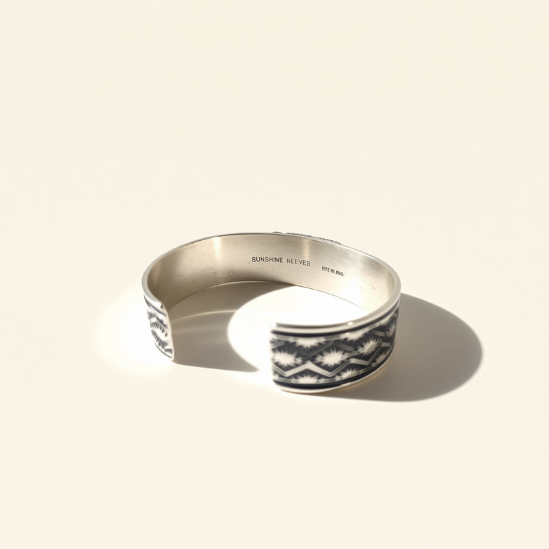 Silver ring with black and white pattern on a beige background