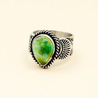 Silver ring with a green stone on a beige background