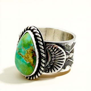 Silver ring with a green stone on a beige background