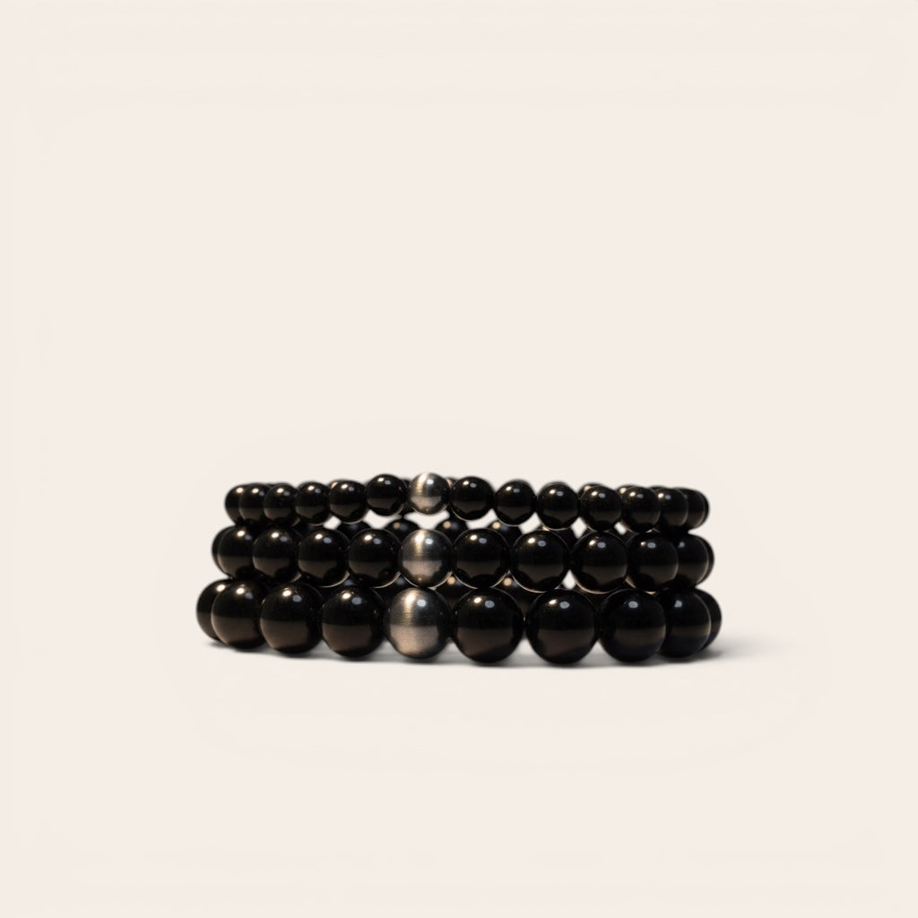 Stack of black beaded bracelets on a beige background