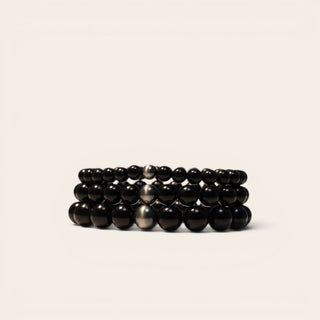 Stack of black beaded bracelets on a beige background