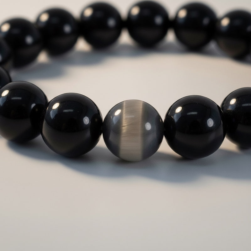 Black beaded bracelet with a unique gray and white bead on a light background