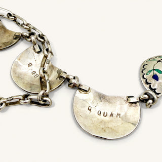 silver jewelry with 'QUAM' stamp on a beige background