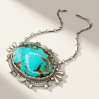 silver necklace with turquoise stone on a beige background