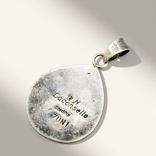 A sterling silver teardrop-shaped pendant with a textured, hammered finish and engraved details including 'R.N.