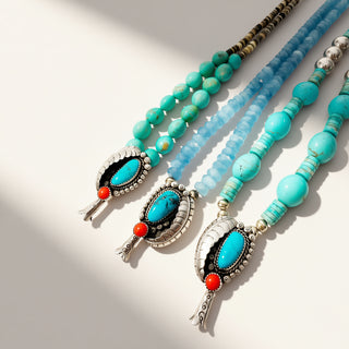 Turquoise beaded necklaces with decorative pendants on a light background