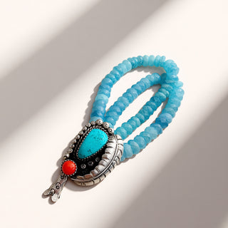 Blue beaded bracelet with a silver clasp and turquoise stone on a white background