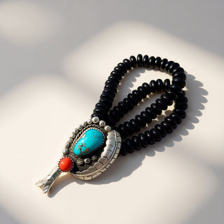 Black beaded necklace with a turquoise and red stone pendant on a light background