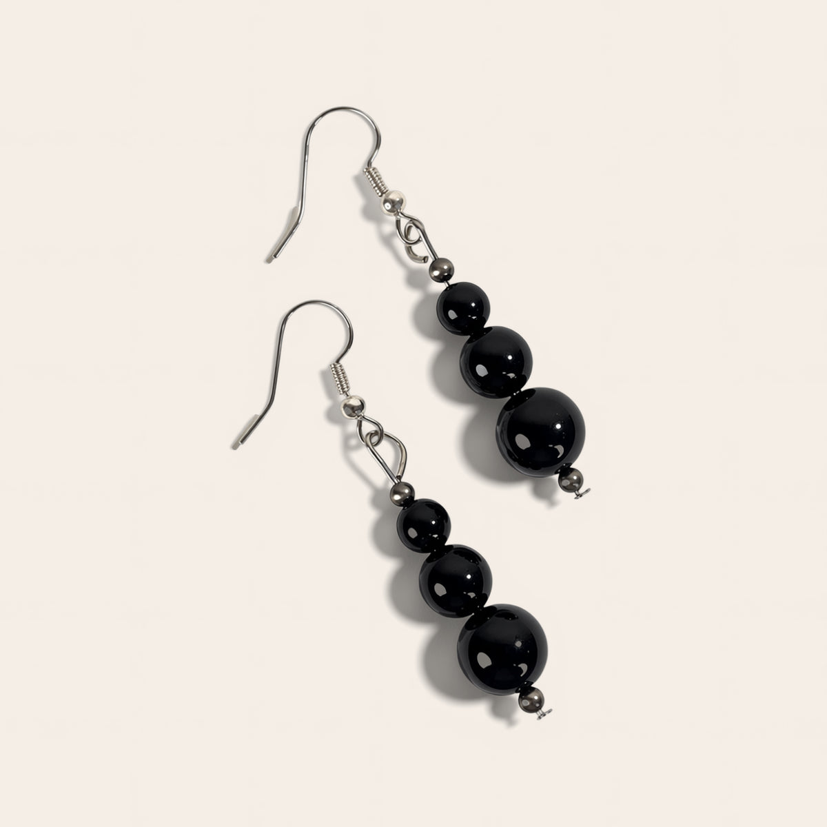 Pair of black beaded earrings on a light beige background