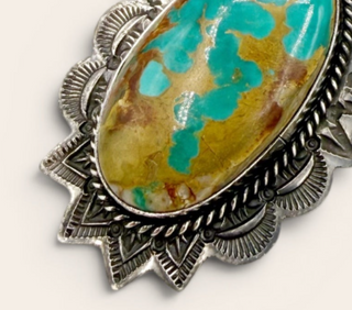 Turquoise stone pendant with silver decorative frame on a white background