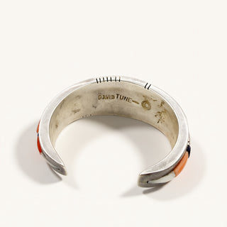 A silver cuff bracelet with orange and black inlay details, photographed on a clean white background. The inside of the bracelet is engraved with 'DAVID TUNE'.