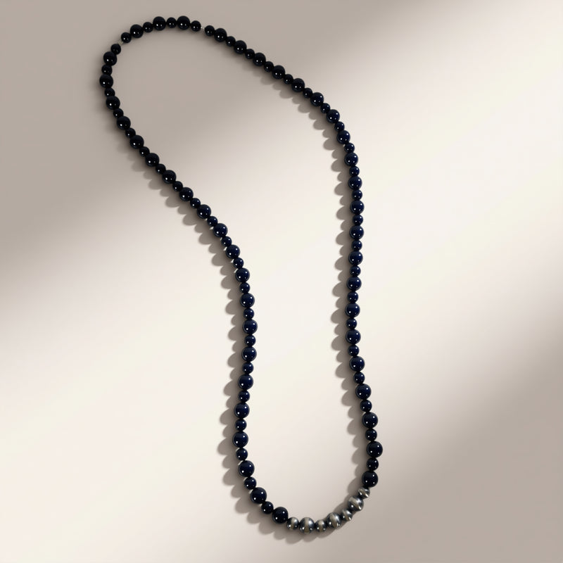 Long necklace with dark beads on a neutral background
