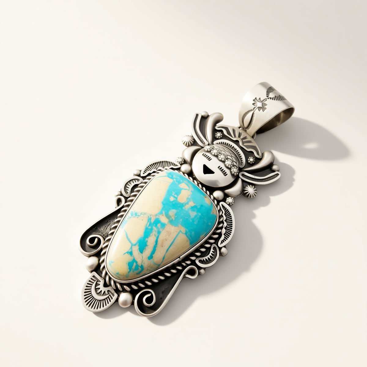 A Southwestern-style silver pendant featuring a turquoise and cream marbled cabochon stone, photographed on a clean off-white background with a soft shadow.