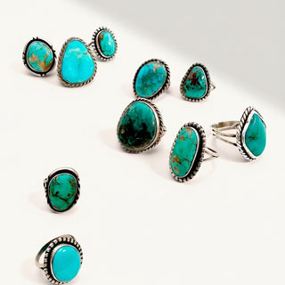 10 silver rings with turquoise stones on a beige background