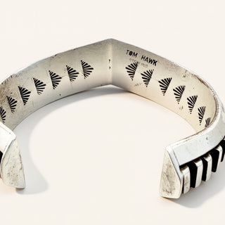 Silver bracelet with engraved patterns on a white background