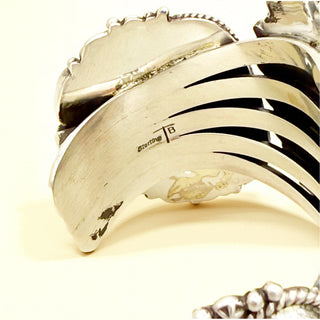 Close-up of a silver bracelet with 'Sterling'  and 'TB' marking on a white background