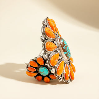 Silver bracelet with orange and turquoise stones on a beige background